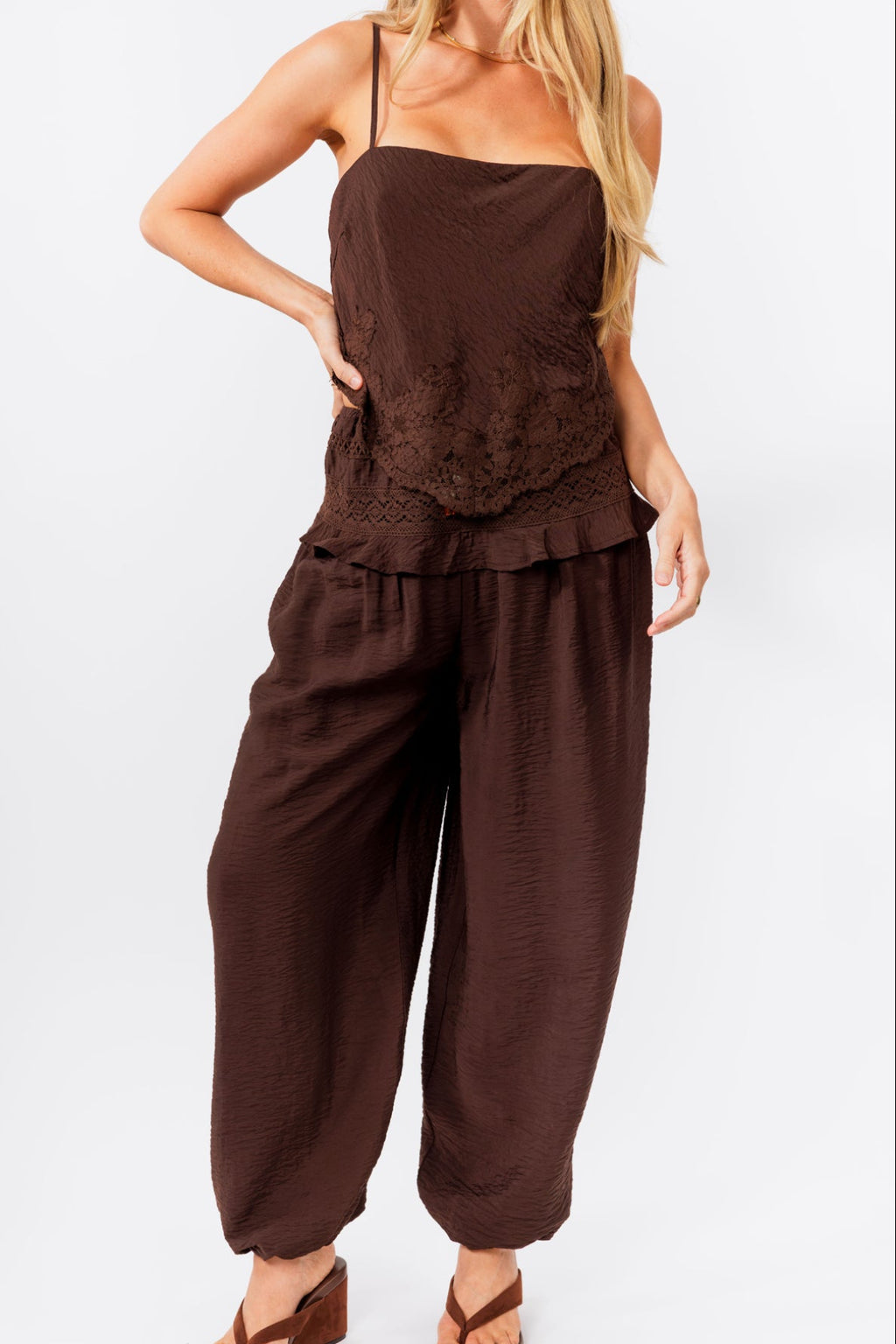 Woman wearing a brown tank and balloon  jogger pant on a white background