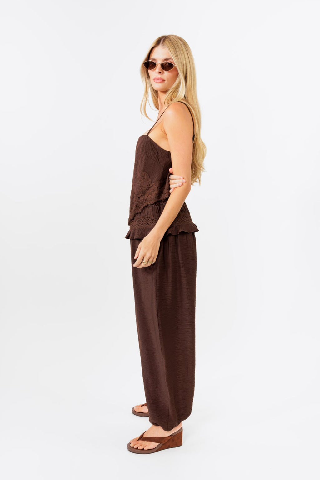 Woman wearing a brown tank and balloon  jogger pant on a white background