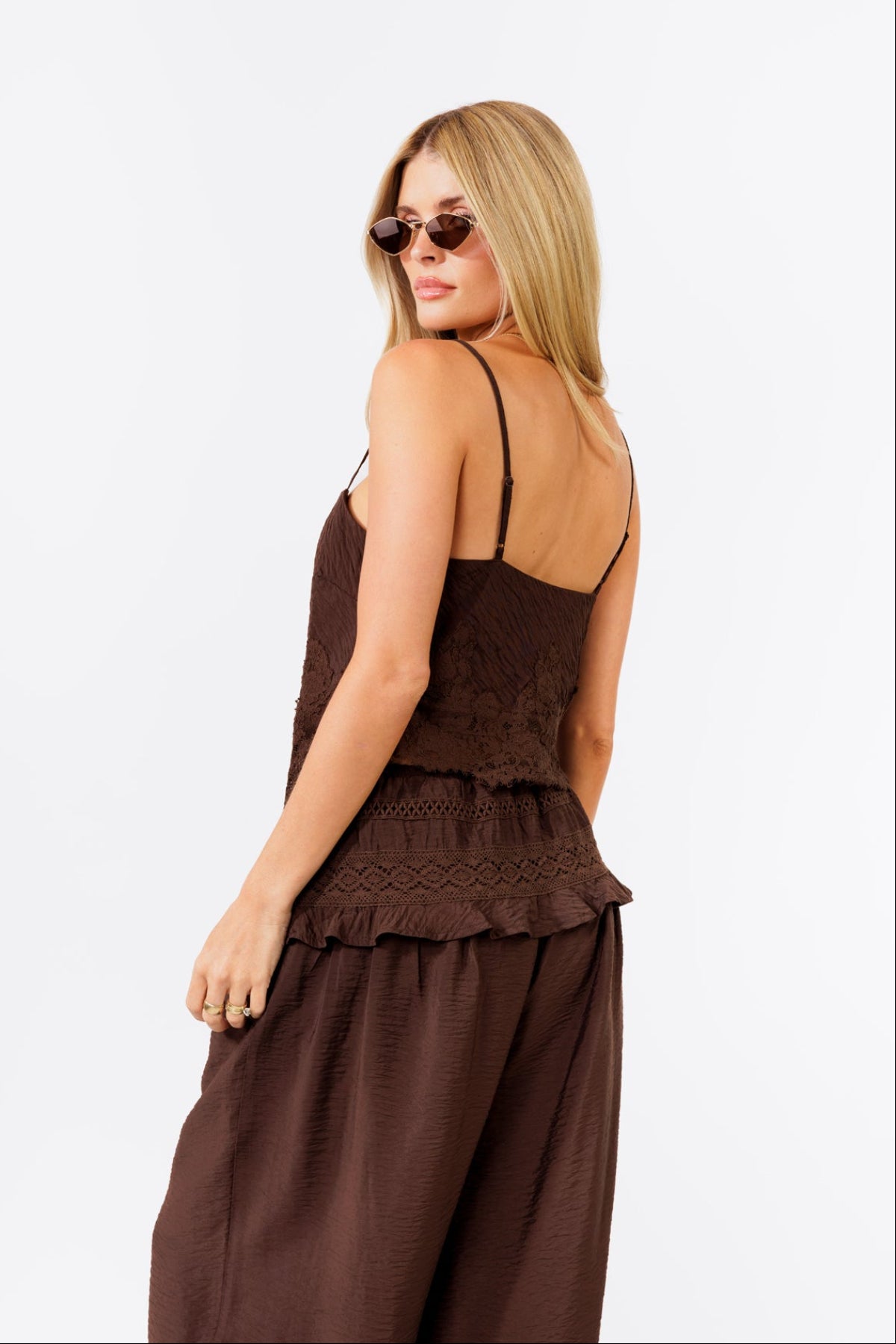 Woman wearing a brown tank and brown jogger pants on a white background