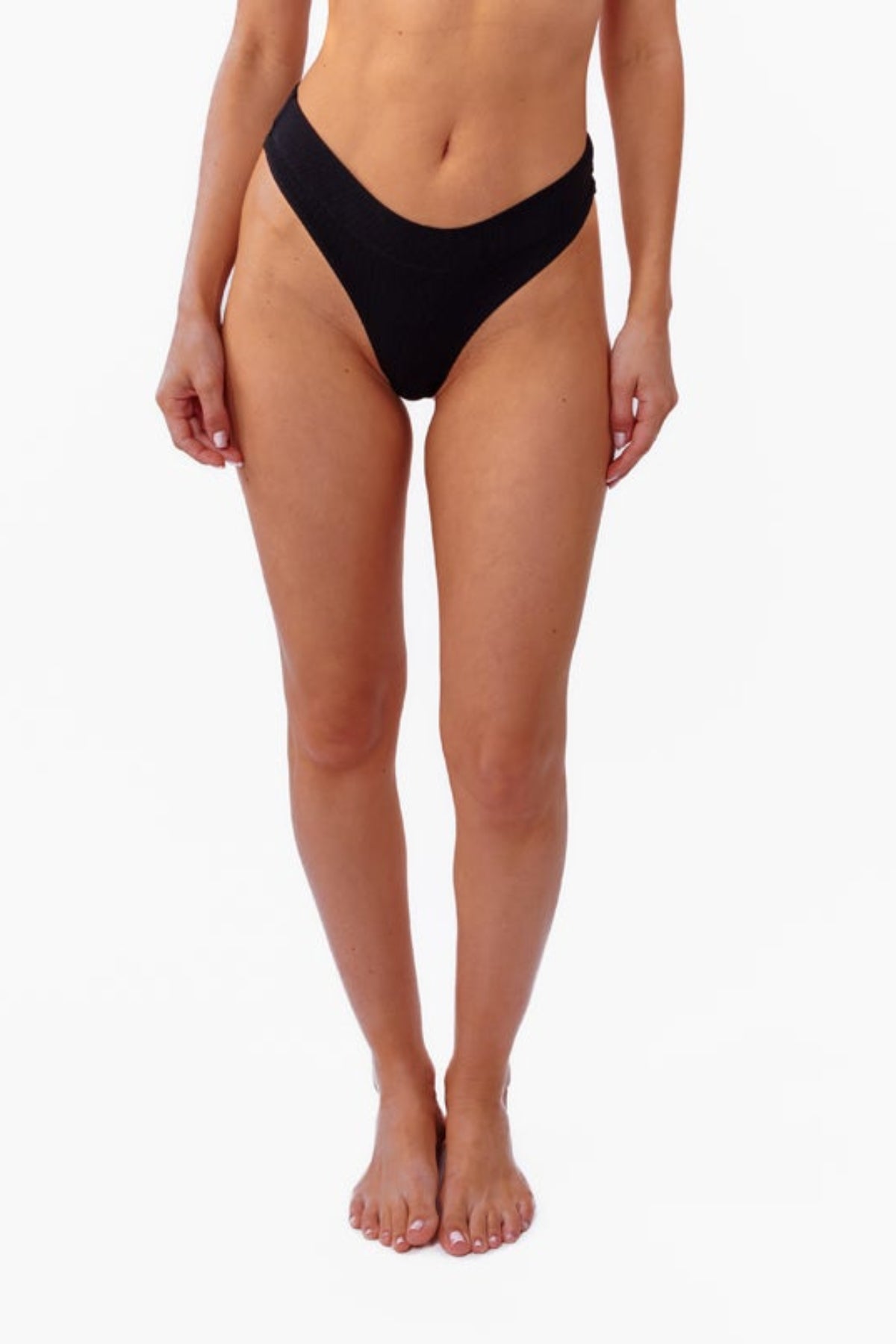 A model wearing a black ribbed thong, shown from the waist down against a plain white background.