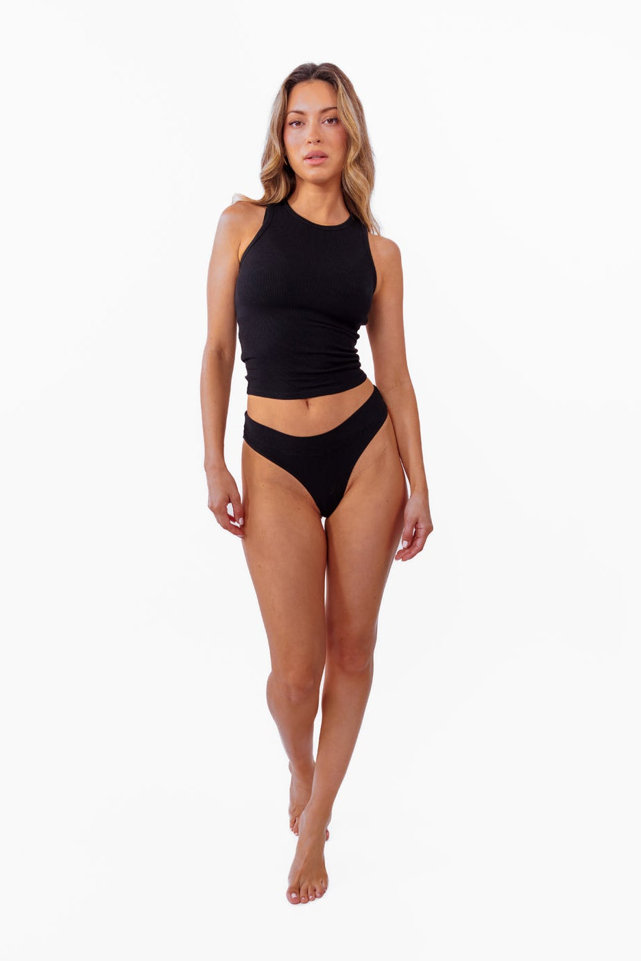 model wearing black ribbed tank with matching thong