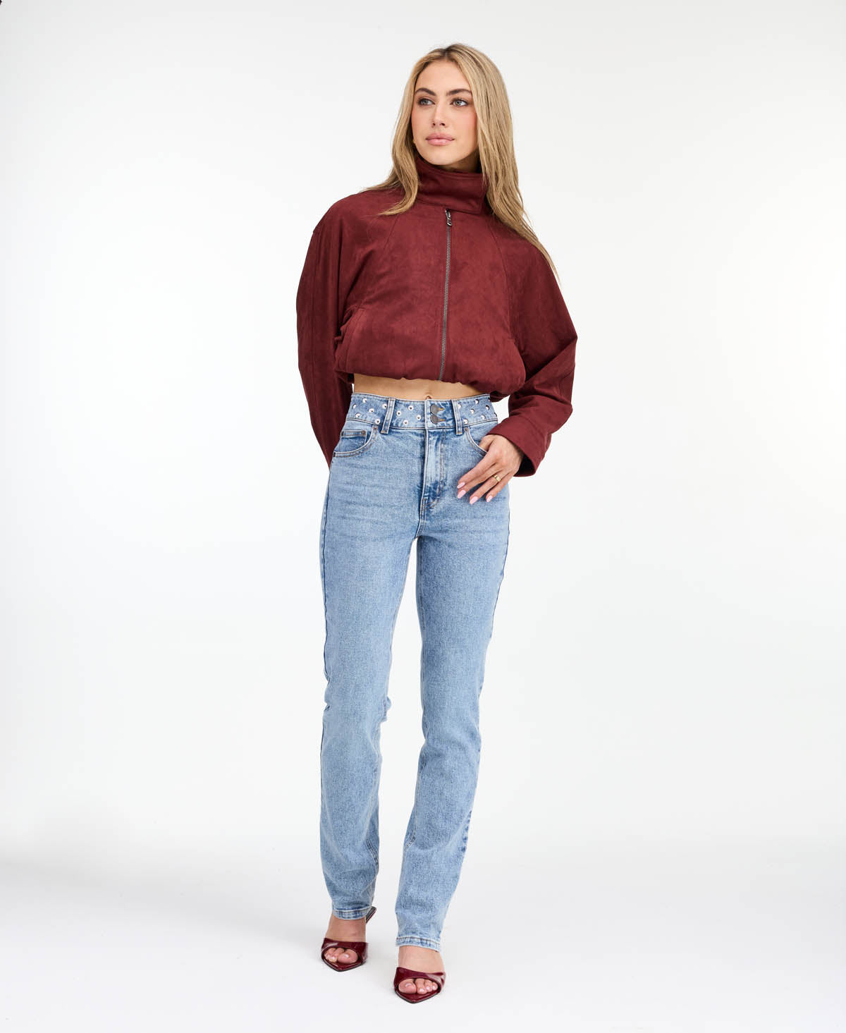 Model wearing high waisted skinny straight leg jeans with a studded waistband paired with kitten heels.