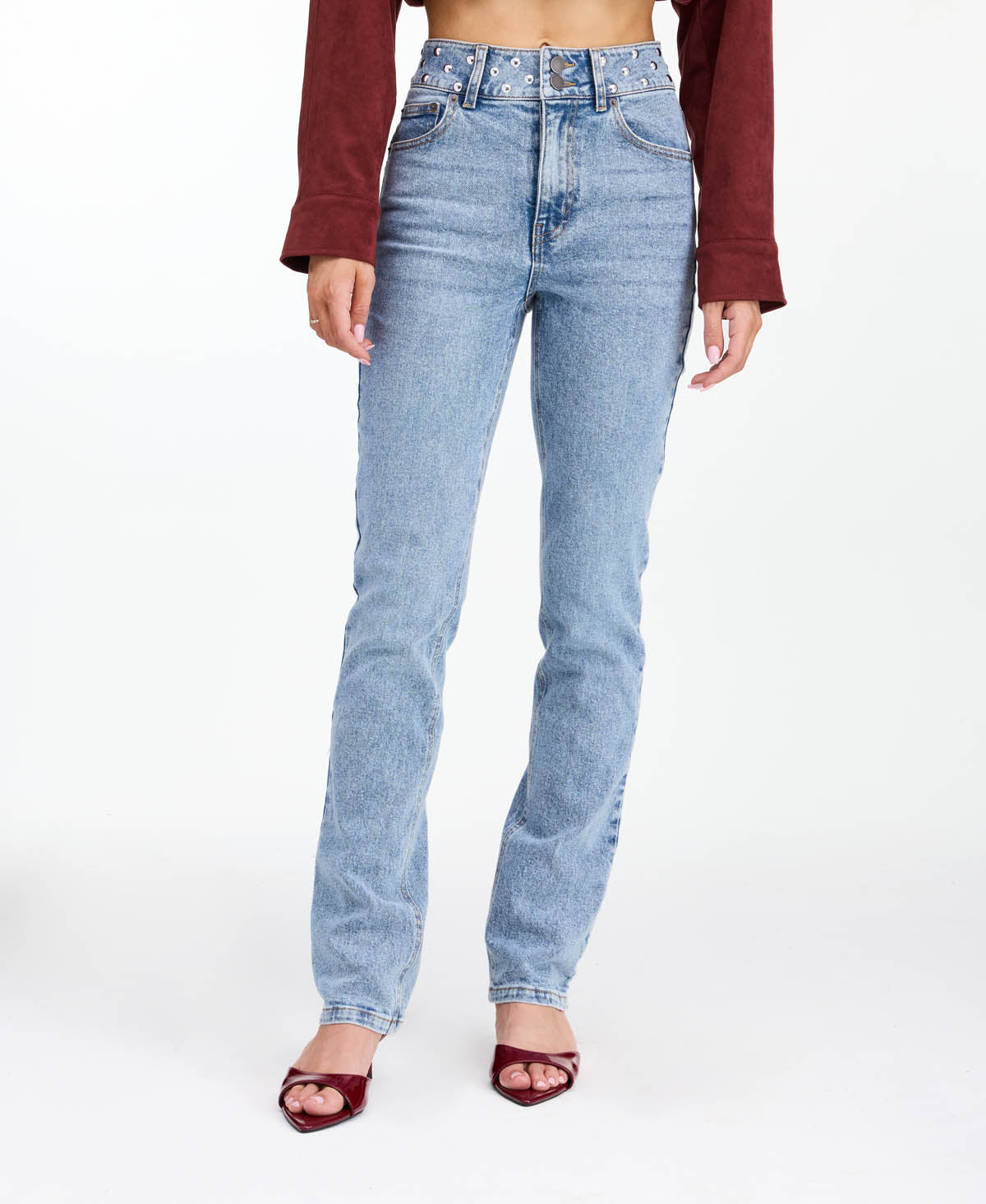 Model wearing high waisted skinny straight leg jeans with a studded waistband paired with kitten heels.