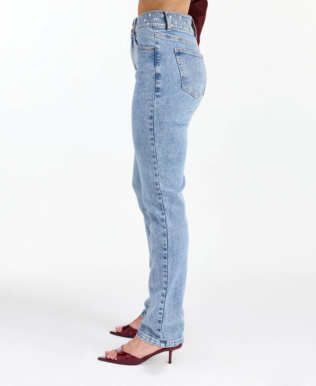 Model wearing high waisted skinny straight leg jeans with a studded waistband paired with kitten heels.