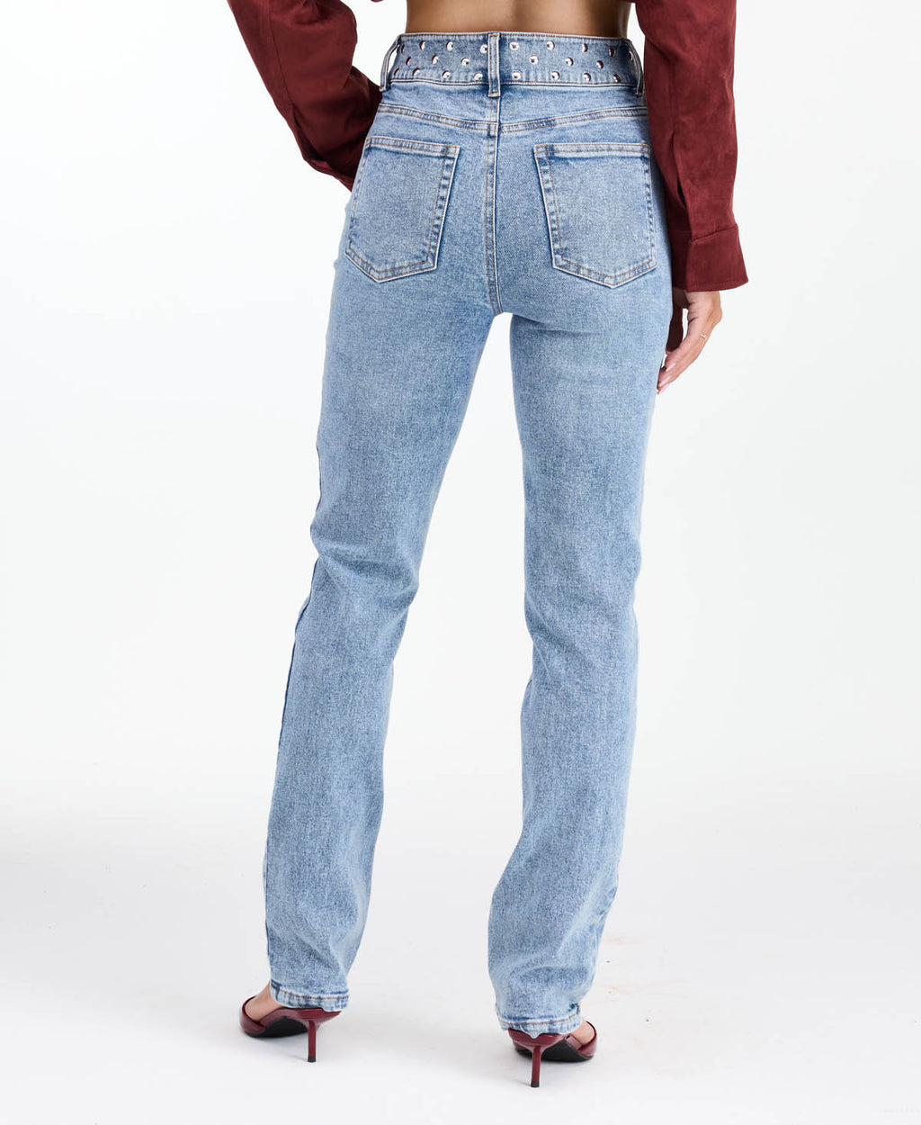 Model wearing high waisted skinny straight leg jeans with a studded waistband paired with kitten heels.
