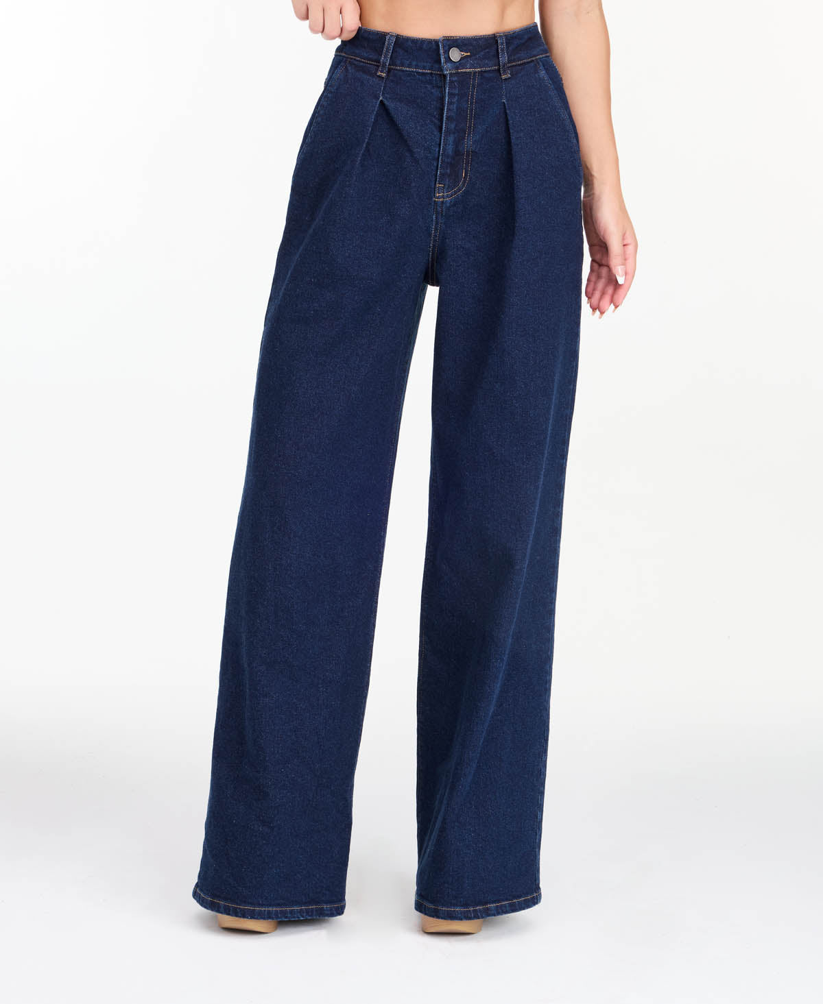 A model wearing dark blue wide-leg denim jeans with a high waist and front pleats, shown from the waist down on a white studio background.