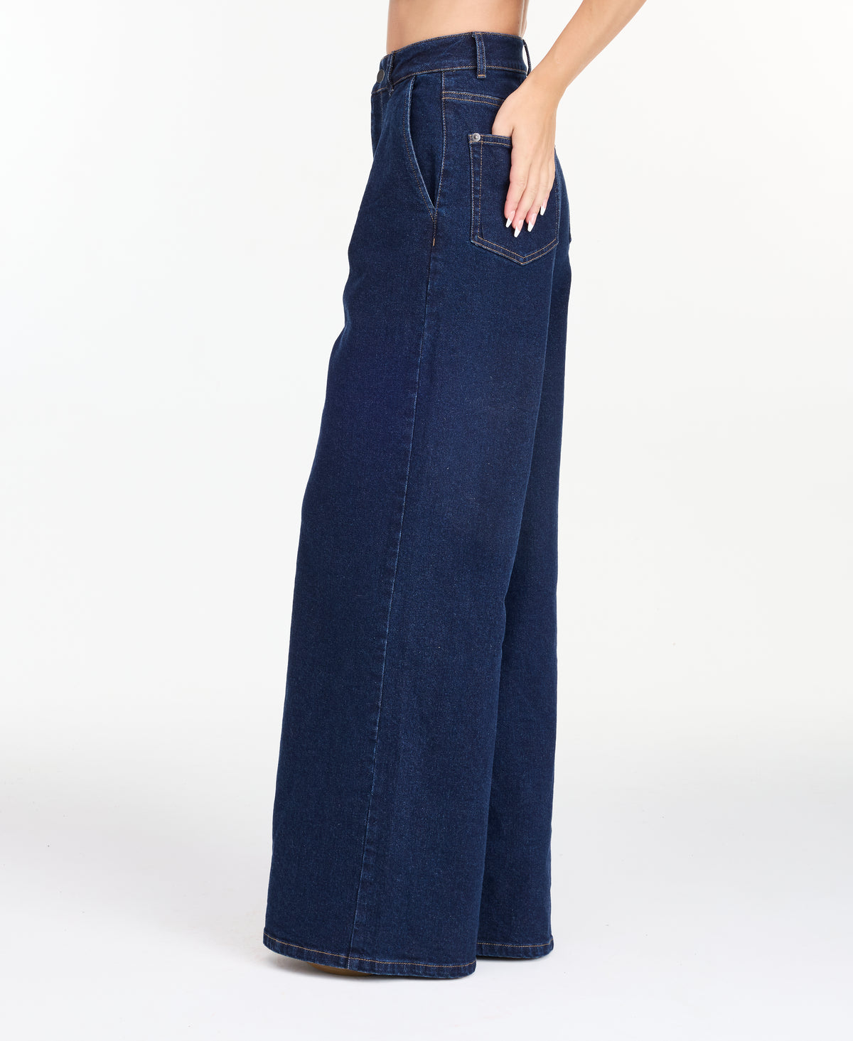 A model wearing dark blue wide-leg denim jeans with a high waist and front pleats, shown from the waist down on a white studio background.