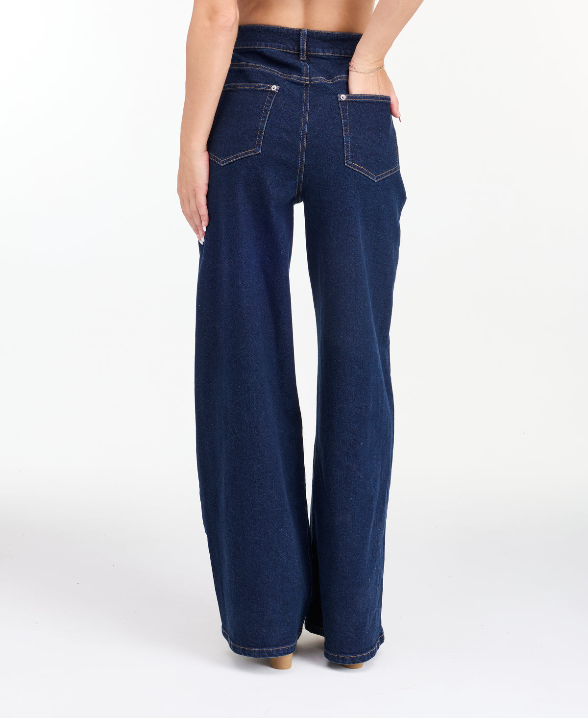  A model wearing dark blue wide-leg denim jeans with a high waist and front pleats, shown from the waist down on a white studio background.