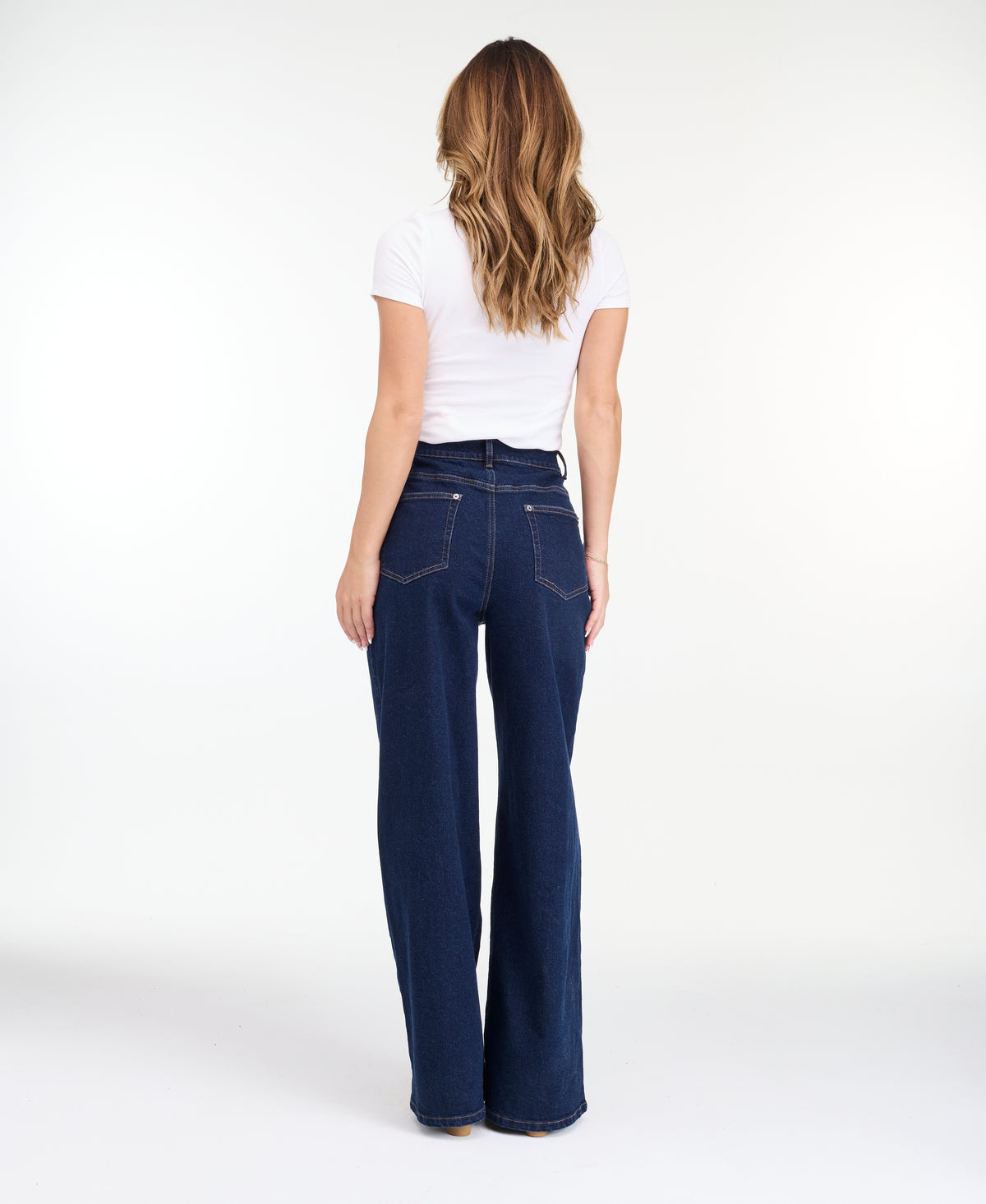 A model wearing dark blue wide-leg denim jeans with a high waist and front pleats, shown from the waist down on a white studio background.