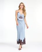Model wearing a blue satin tank with chocolate brown embroidered appliqué and a matching midi skirt standing against a white background