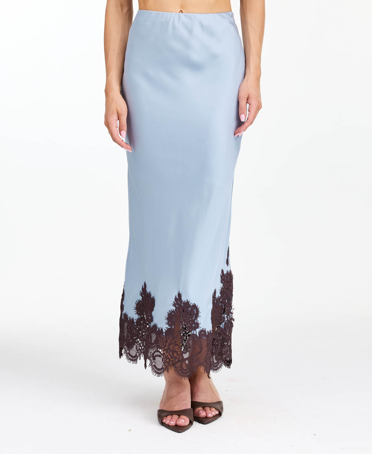 Model wearing a blue satin midi skirt with brown lace appliqué at the hem
