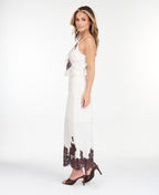 A woman modeling a white midi with dark brown lace detailing on the bodice of tank and hem, standing against a plain white studio background.