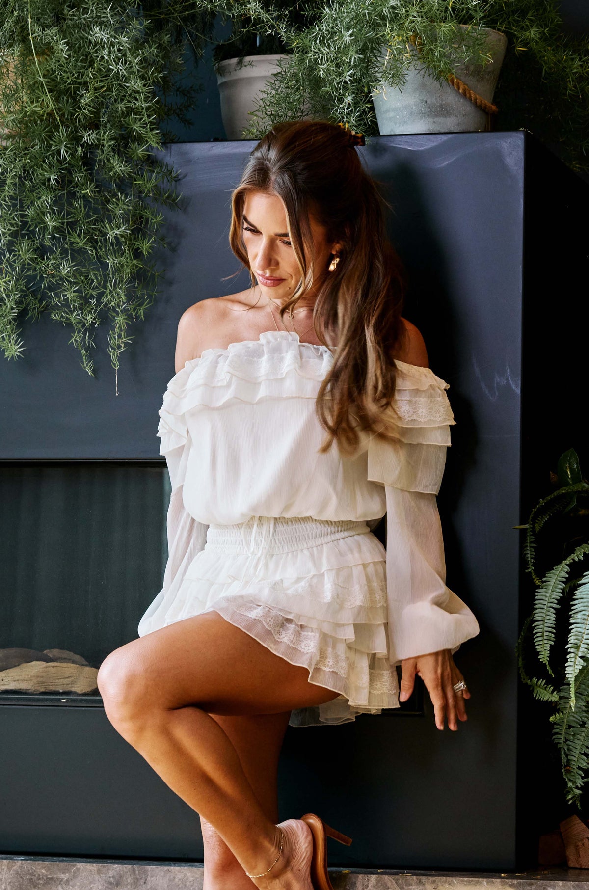 Jessie wearing an ivory off shoulder dress with lace and ruffle details