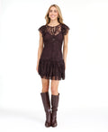 A woman modeling a dark brown lace mini dress with ruffled cap sleeves and tie detail at the neckline, paired with dark brown knee-high boots, against a plain white studio background.