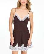 A woman modeling a short brown ribbed mini dress with white lace trim along the neckline and hem, paired with dark brown heeled sandals, against a plain white studio background.