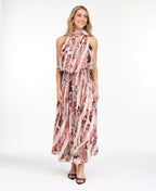 Model wearing a pink snake print midi dress with a smocked waistband and neck scarf standing against a white backdrop