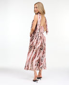 Model wearing a pink snake print midi dress with a smocked waistband and neck scarf standing against a white backdrop