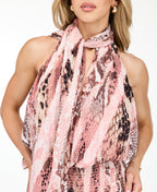 Model wearing a pink snake print midi dress with a smocked waistband and neck scarf standing against a white backdrop