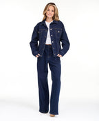 A model wearing dark blue wide-leg denim jeans with a high waist and front pleats, shown from the waist down on a white studio background.