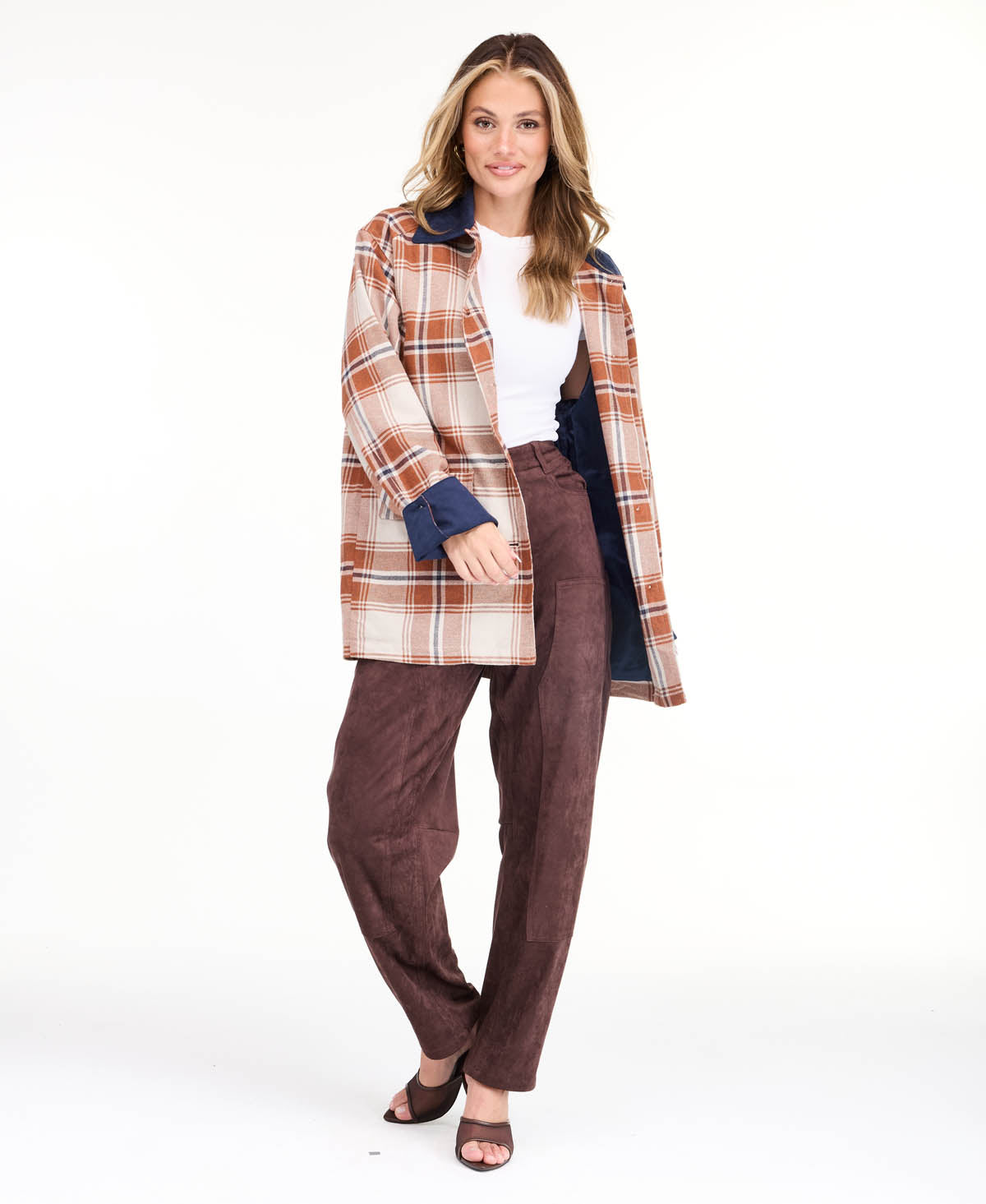 Model wearing a light brown plaid coat with navy blue contrast lapels and cuffs, styled over a white top and brown pants against a plain white background.