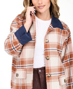 Model wearing a light brown plaid coat with navy blue contrast lapels and cuffs, styled over a white top and brown pants against a plain white background.