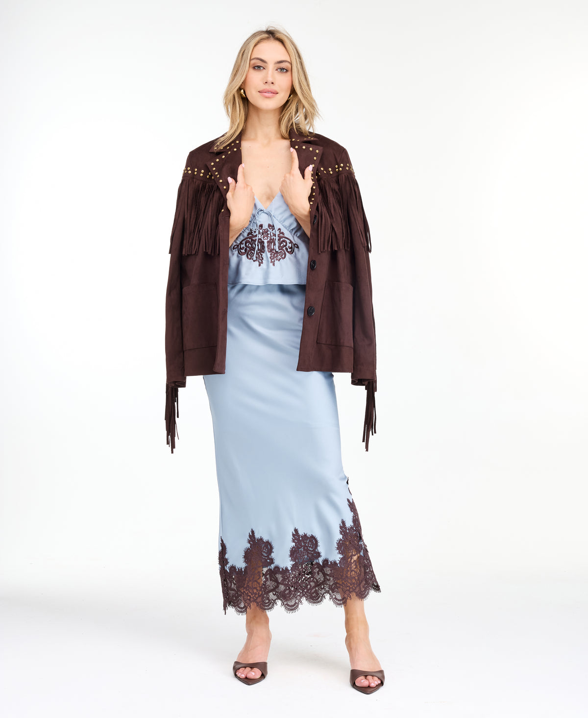 Model wearing a blue satin tank with chocolate brown embroidered appliqué and a matching midi skirt standing against a white background