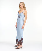 Model wearing a blue satin tank with chocolate brown embroidered appliqué and a matching midi skirt standing against a white background