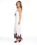 A woman modeling a white tank with matching midi skirt with dark brown floral lace on the bodice and hem, set against a plain white studio background.