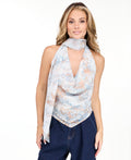 A woman modeling a light blue sleeveless halter top with a textured pattern and removable scarf  and light-wash wide-leg denim pants against a plain white studio background.