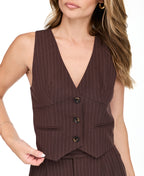 A woman modeling a dark brown pinstriped sleeveless vest-style top and barrel pants, standing against a plain white studio background.