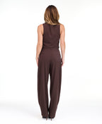 A woman modeling a dark brown pinstriped sleeveless vest-style top and barrel pants, standing against a plain white studio background.