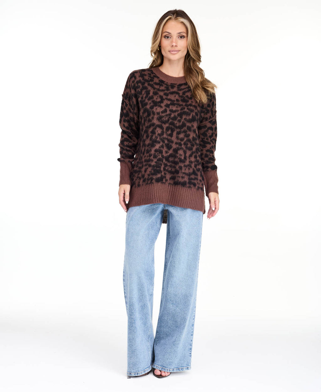 Model wearing an oversized  cheetah crew neck sweater with medium wash denim jeans.