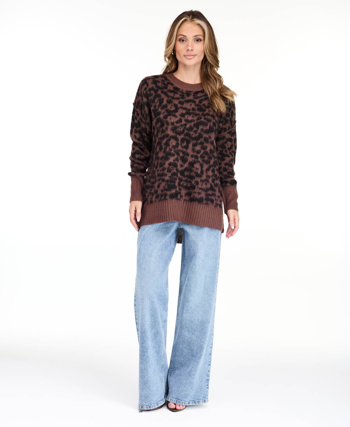 Model wearing an oversized  cheetah crew neck sweater with medium wash denim jeans.