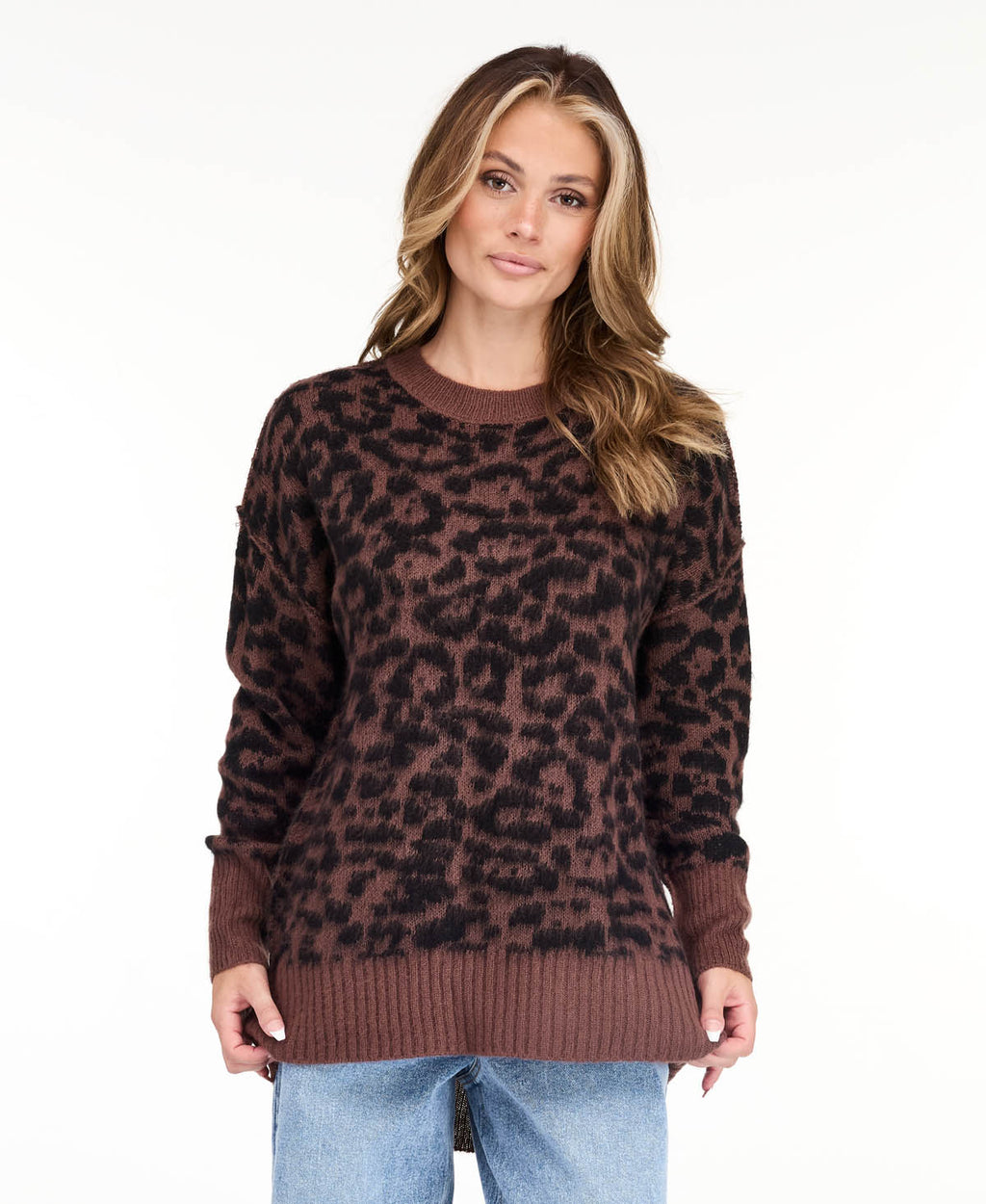 Model wearing an oversized  cheetah crew neck sweater with medium wash denim jeans.
