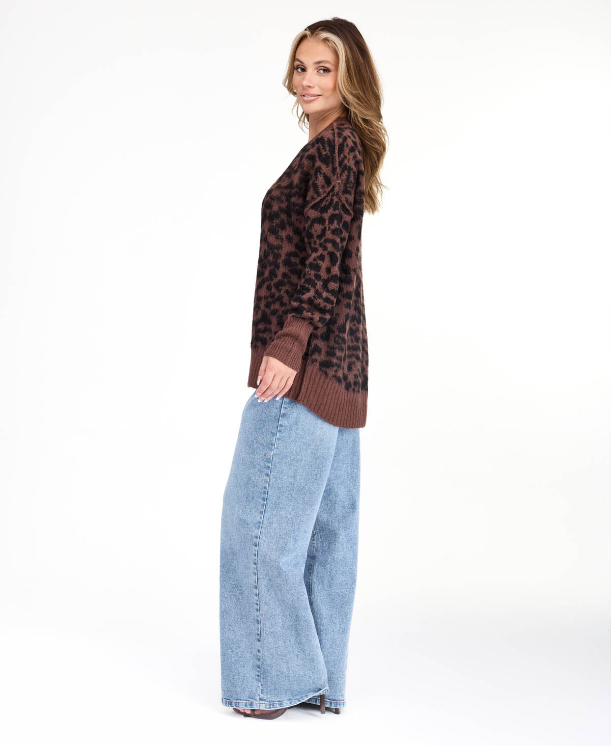 Model wearing an oversized  cheetah crew neck sweater with medium wash denim jeans.
