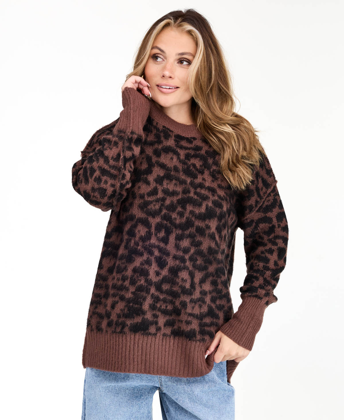 Model wearing an oversized  cheetah crew neck sweater with medium wash denim jeans.