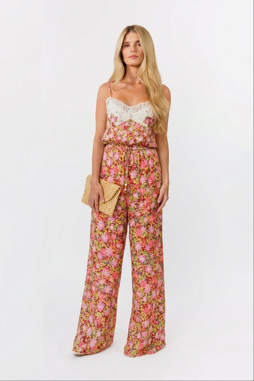 Woman wearing a floral jumpsuit with a white lace top on a white background