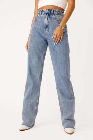 Model wearing 'Beau' light wash high-rise raw hem denim jeans.
