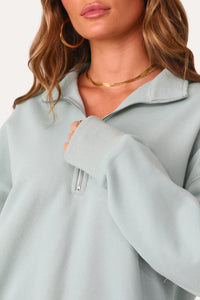 Model wearing Bubbly Blue Half Zip Logo Pullover.