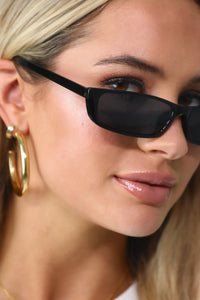 Model wearing the Carrie thin black sunglasses.