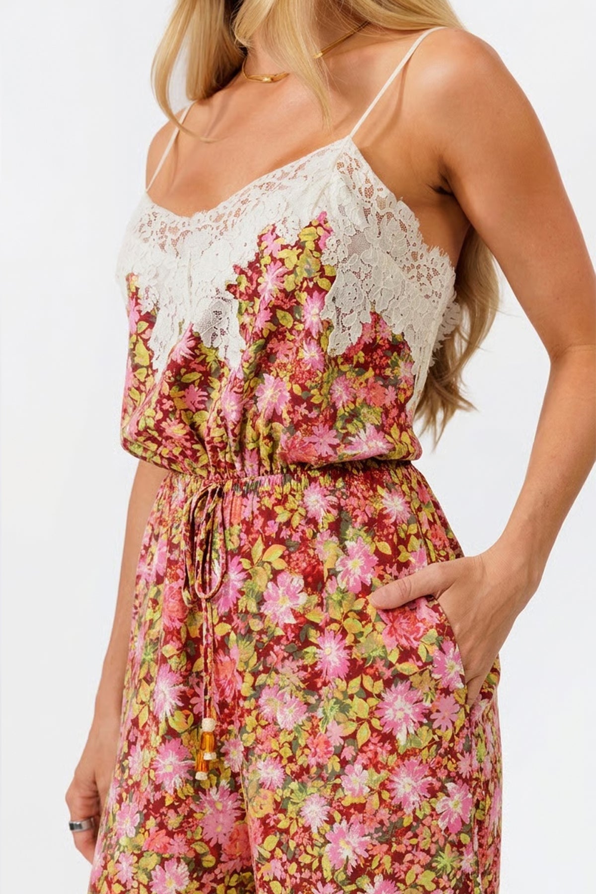 Woman wearing a floral jumpsuit with lace details on a white background