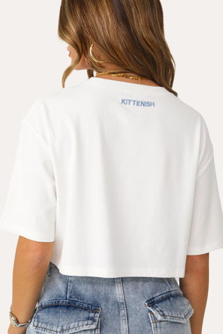 Model wearing White Ribbed Crop Shirt with Blue Logo.