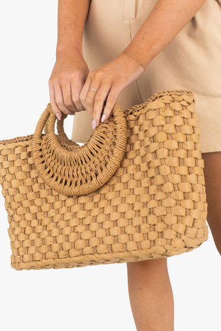 Close up image of model holding the Natural Woven tote. 