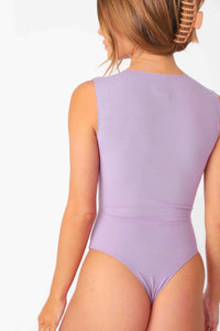 Model wearing Lilac Ribbed Sleeveless Tank Bodysuit, stretchy rib knit seamless fabrication, with crew neckline and thong coverage.
