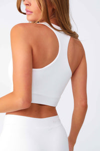 Model wearing White Cropped Seamless Rib Bra Tank, stretchy rib knit seamless fabrication, with v-neckline and racerback.