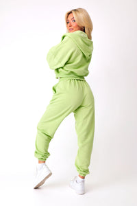 Back Front view of model wearing green KiKi Joggers, paired with matching KiKi full zip and razorback tank.