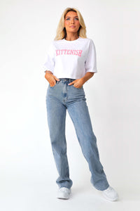 Full body front view of model wearing the Pink Varsity Logo Cropped Tee paired with the Beau light was denim jeans.