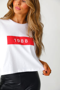 Close up image of model wearing white and red '1988' cropped tee with 'Bet On Me' black faux leather leggings. 