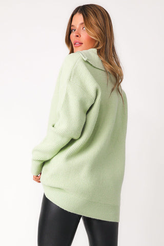 Close up back view of model wearing lime green 'Lean On Me' quarter zip sweater. Paired with 'Bet On Me' leather leggings.