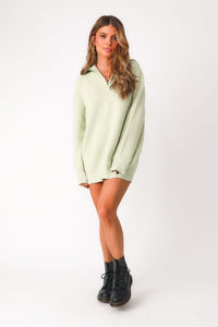 Full body front view of model wearing lime green 'Lean On Me' quarter zip sweater. Worn as dress paired with  boots. 